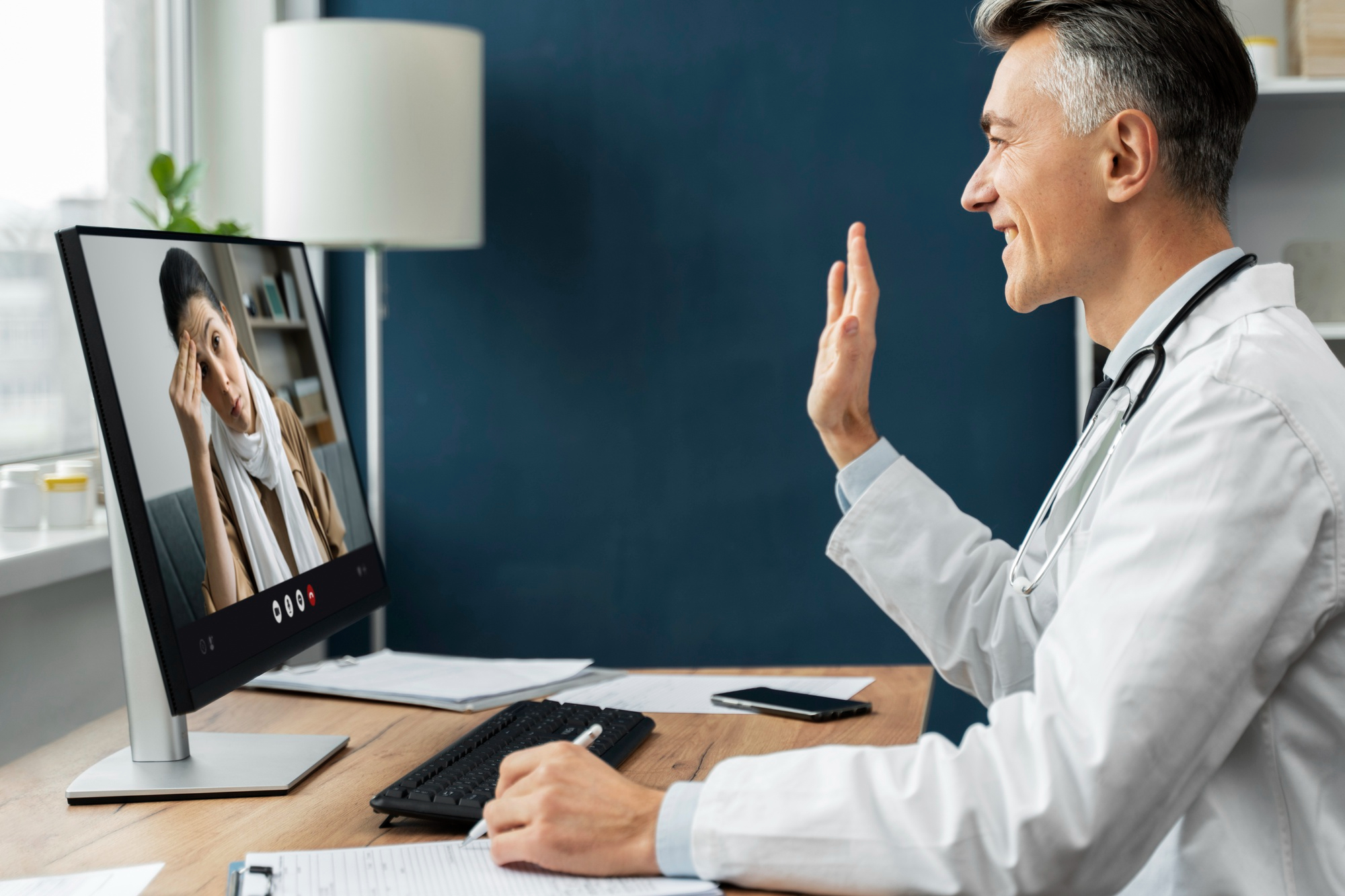 Médico em frente a um compjutador, atendendo uma paciente por telemedicina.