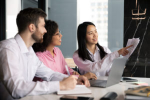 Três pssoas sentadas ao redor de uma mesa de estudos, discutindo sobre Treinamento de Secretariado Médico.